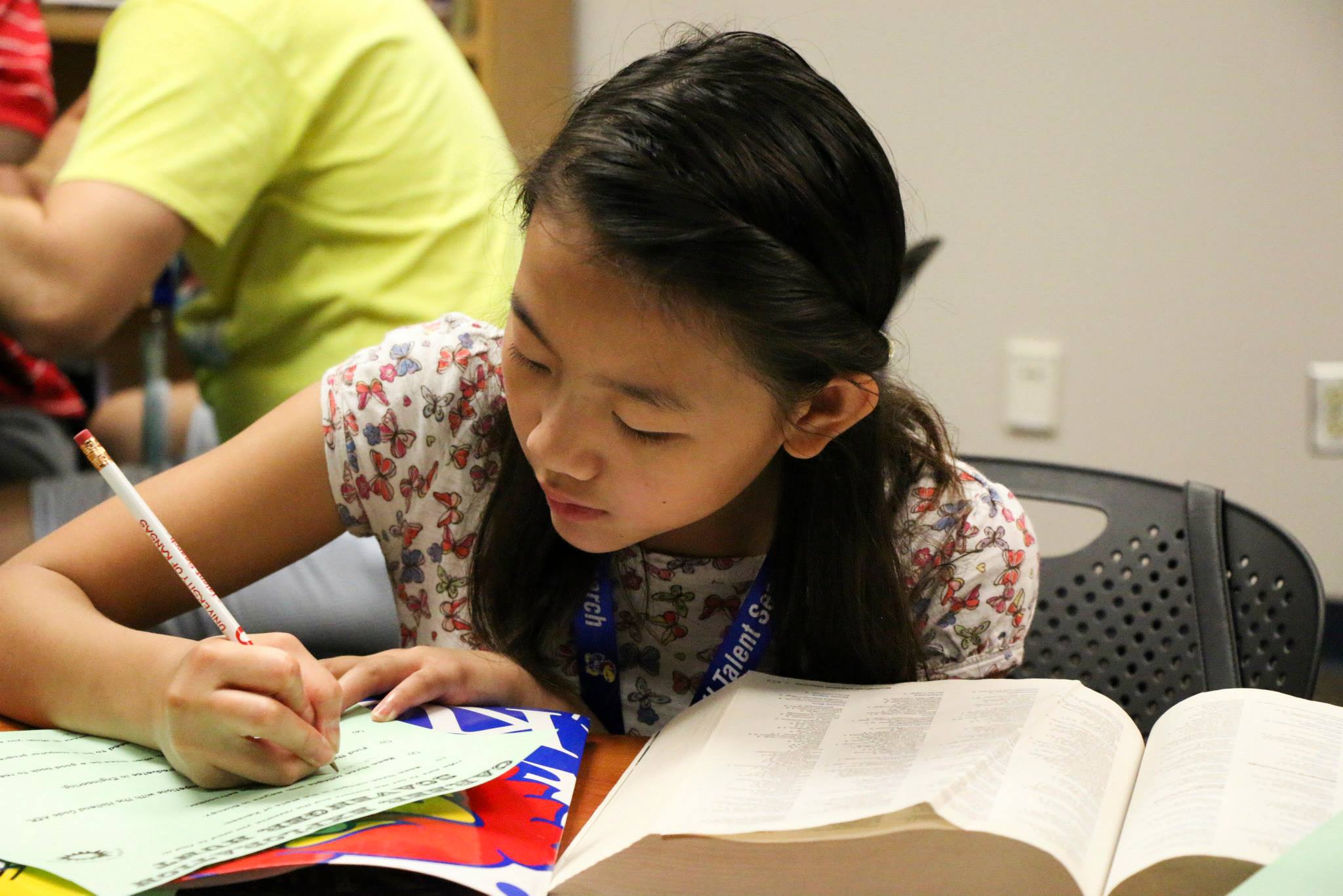 A middle school student with a big book and writing with a pencil