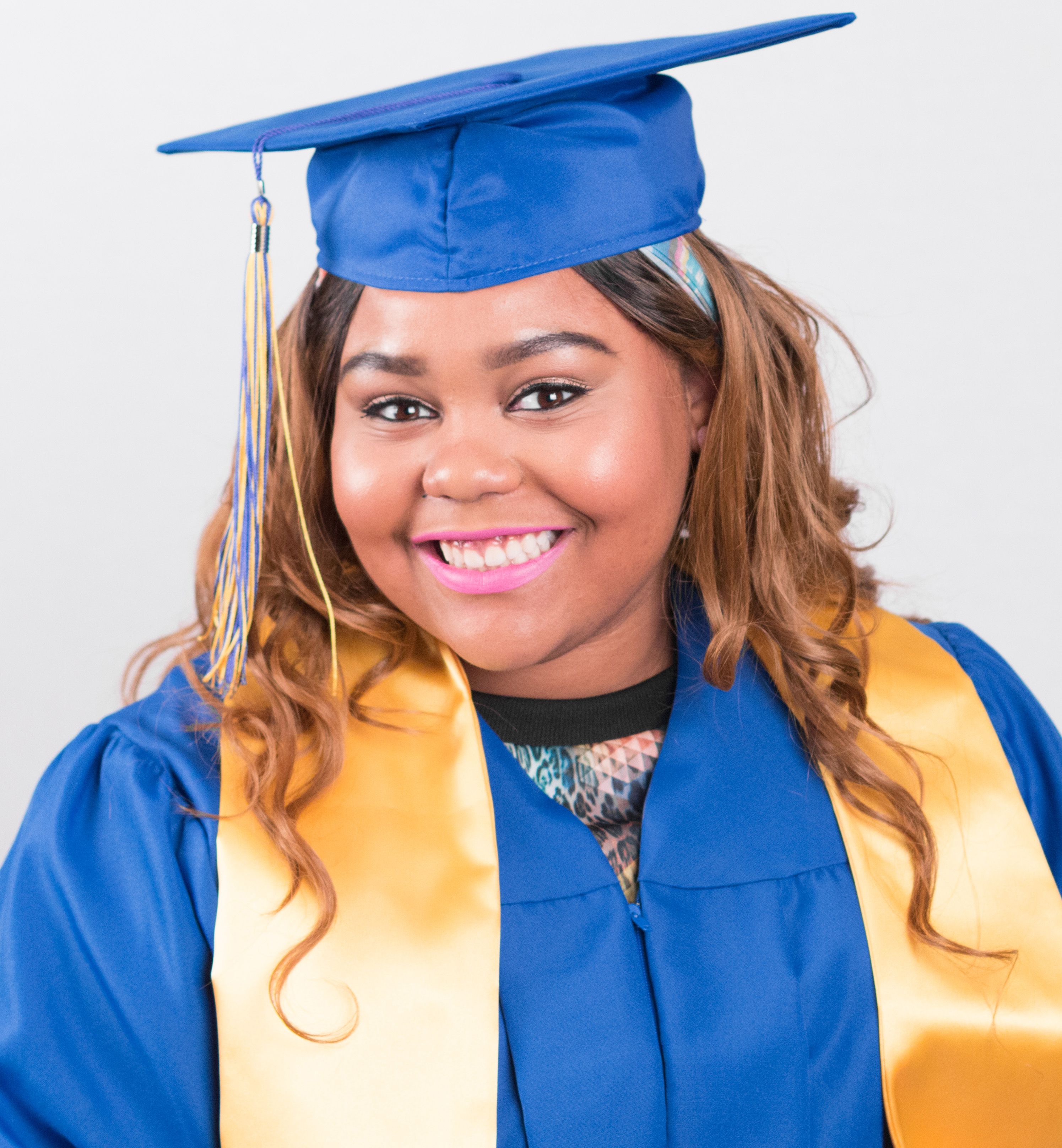 A photograph of Dovie wearing a blue and yellow graduation cap and robe