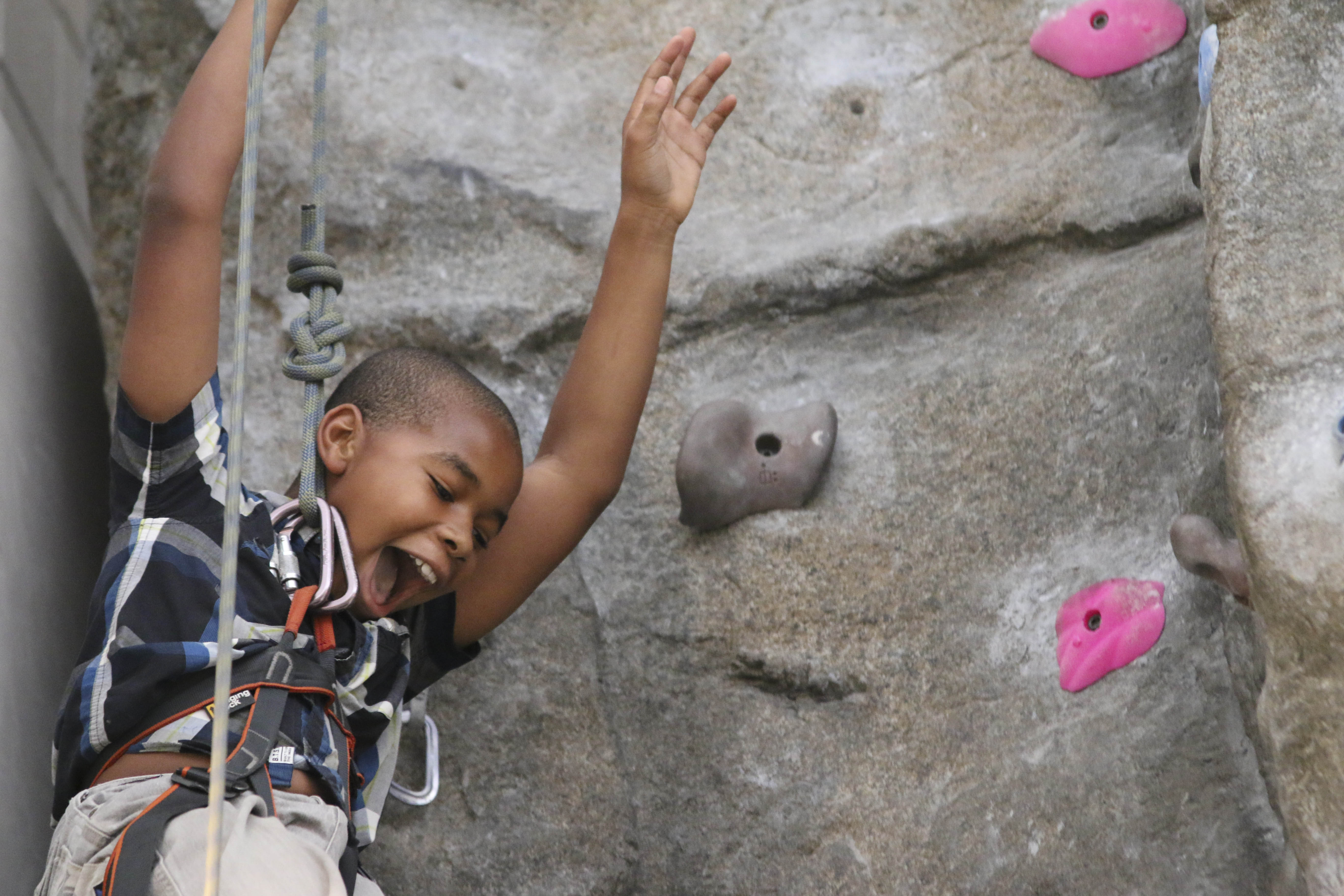 A student celebrating reaching the top of a rock wall